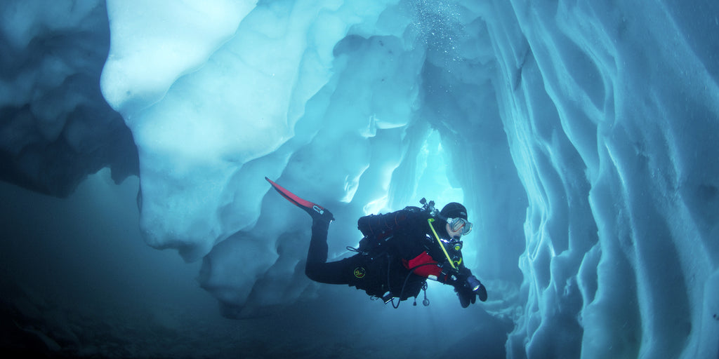 A man scuba diving in cold water under ice