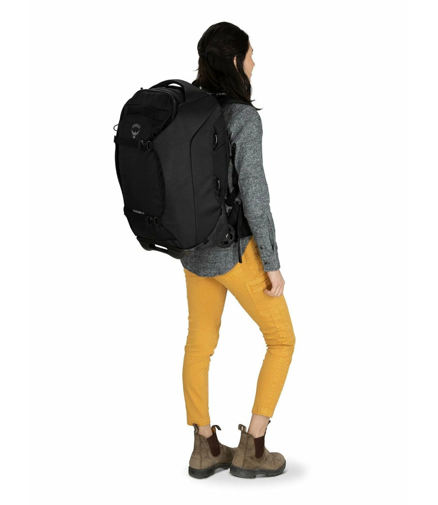 Woman wearing Sojourn wheeled travel pack in black