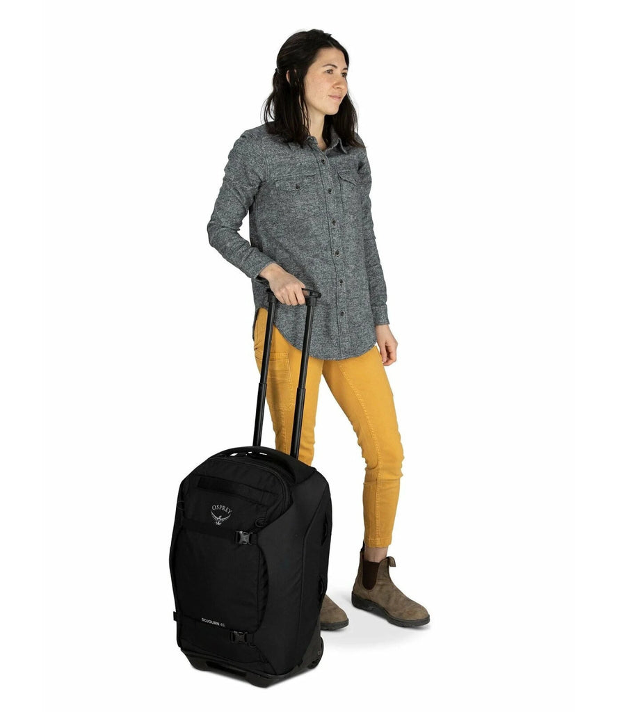Woman with black Osprey Sojourn wheeled travel pack