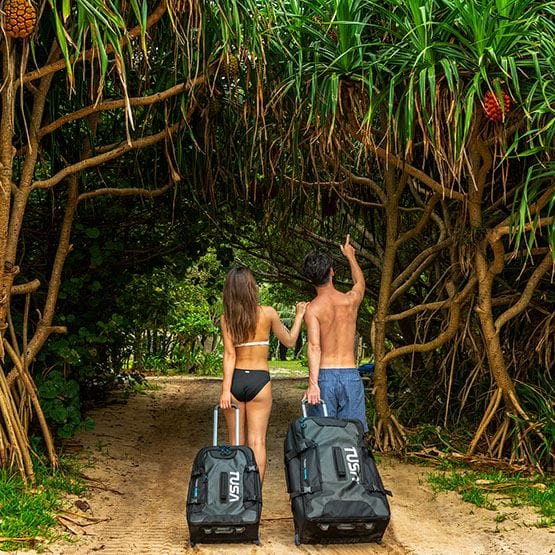 Couple with luggage walking under tropical trees